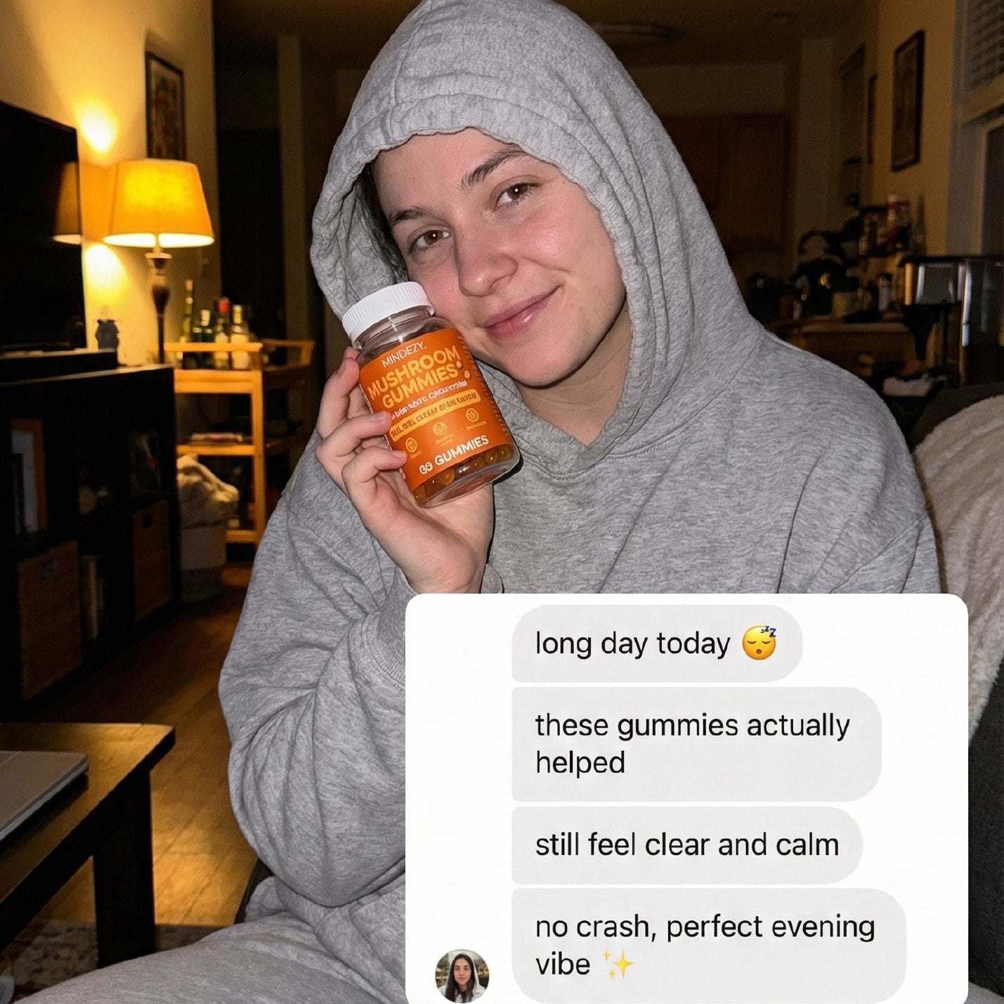 Person in a gray hoodie holding a jar of gummies in a living room.